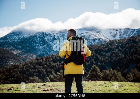 Junger Mann mit gelber Jacke und Rucksack in den Bergen. Stockfoto