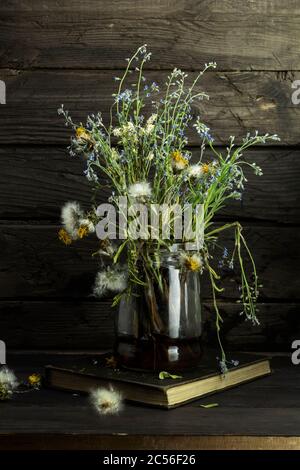 Stillleben mit Blumen. Blumenstrauß im Glas auf Holztisch. Stockfoto