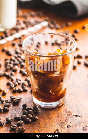 Gefrorener Kaffee in Herzform. Kaffeeeiswürfel in Glasbecher und Kaffeebohnen. Stockfoto