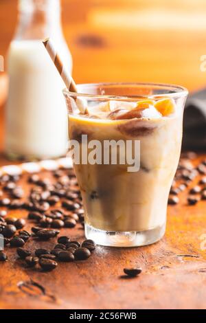 Eiskaffee mit Kaffeeeiswürfeln auf Holztisch. Stockfoto