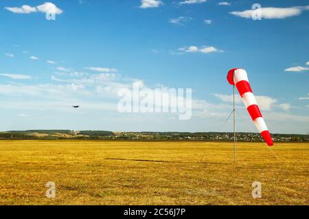 Rot-weiße Windsack Wind Socke auf blauen Himmel auf dem Flugplatz, gelbe Feld und Wolken Hintergrund Stockfoto