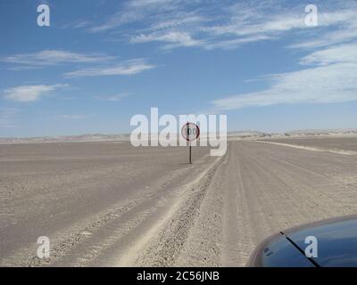 Sonnige Landschaft einer Wüstenstraße mit einem Tempolimit Wegweiser in Skeleton Coast, Namibia, Afrika Stockfoto