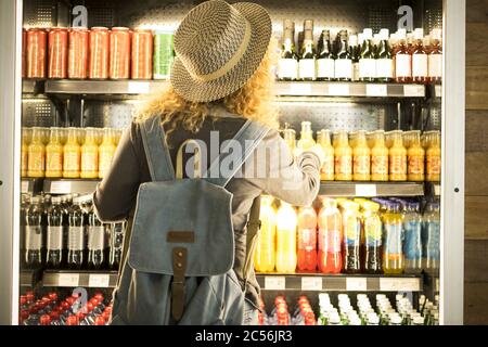 Reisefrau von hinten gesehen, ich hatte ein Getränk in einem frischen Kühlschrank - Flughafen oder Bahnhof Bar Konzept und Reisende Passagiere Auswahl Getränke - moderne lif Stockfoto