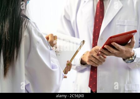 Nahaufnahme eines Oberarztes, der seinen jüngeren Kollegen einen Rat zur Diagnose im Klinikkrankenhaus gibt. Konzept der Healthcare Teamarbeit. Stockfoto