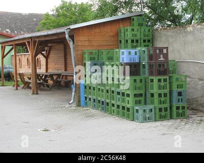 Bündel von Kunststoff-Lagerboxen in der Nähe einer Holzkonstruktion mit Tisch und Stühle Stockfoto