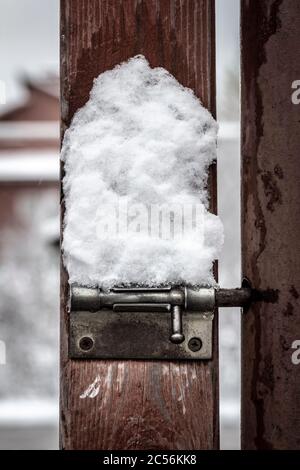 Ein einfacher Metallfang auf einem Landtor ist mit Schnee bedeckt. Stockfoto