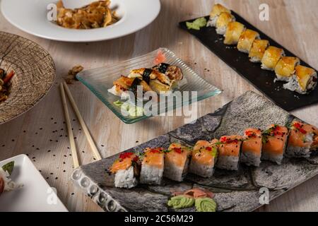 Große Auswahl an Sushi-Brötchen auf verschiedenen Tellern serviert Essstäbchen Stockfoto