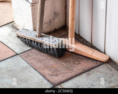 In der Ecke stehen ein alter Holzpinsel und ein Mopp. Stockfoto