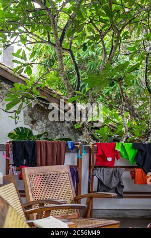 Sitzecke auf einer Terrasse unter einem Feigenbaum und hängende Wäsche zum Trocknen Stockfoto