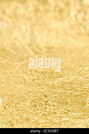 Nahaufnahme der zerknitterte Oberfläche der goldenen Zinnfolie. Fokus auf der Vorderseite, selektiver Fokus. Abstrakter strukturierter Hintergrund im Vollformat. Stockfoto