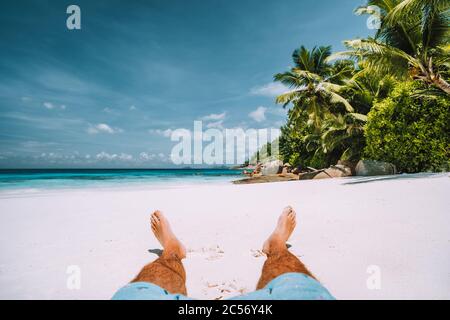 Mann, der sich am weißen Sandstrand mit wunderschönen Palmen ausruhte. Stockfoto