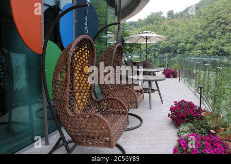 Wicker Korb Schaukel Stühle auf einer Terrasse am See Stockfoto