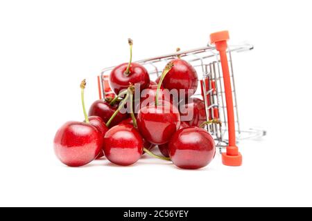 Nahaufnahme von Süßkirschen in einem Miniatur-Spielzeug-Shopping-Trolley isoliert auf weißem Hintergrund. Konzept für die Lieferung von frischem Obst. Stockfoto