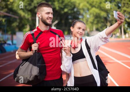 Lächelnder Junge und schönes Mädchen glücklich, Fotos auf Frontalkamera des Mobiltelefons, während freudig verbringen Zeit zusammen im Stadion Stockfoto