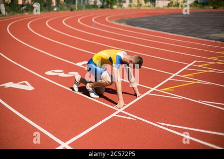Junger Profi-Sportler in Startposition bereit für das Laufen auf Laufband des Stadions Stockfoto