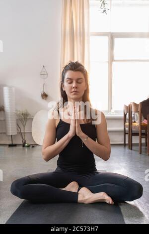 Ruhige junge Frau meditiert auf Yoga-Matte Stockfoto