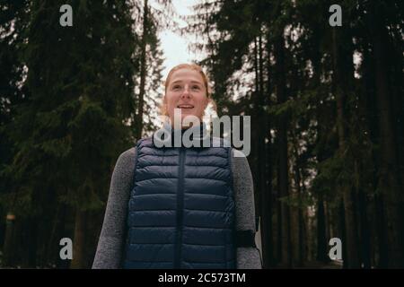 Portrait selbstbewusste, lächelnde Läuferin im Wald Stockfoto