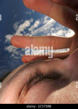 Nahaufnahme Frau, die die Augen mit der Hand unter sonnigem Himmel abschirmt Stockfoto
