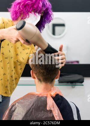 Konzept: Entbindung nach Coronavirus, covid-19. Detail der Hände des professionellen Friseurs. Trocknen von Haaren auf Frau mit kurzen hai Stockfoto