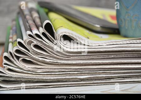 Stapel von Zeitungen mit einer Tasse Kaffee und ein Smartphone isoliert auf einer Holzoberfläche Stockfoto