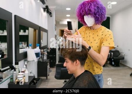 Konzept: Entbindung nach Coronavirus, covid-19. Professionelle Friseur schneiden Haare von braunen kurzhaarige Frau im Friseursalon. Stockfoto