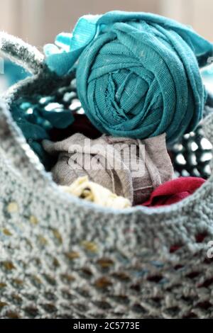 Nahaufnahme Ball aus Garn in der Tasche aus Recycling alten T-Shirt, Spaß Freizeit mit hausgemachten Wiederverwendung von geschnittenen Kleidung in Garnen, bunte Szene in Sonnenlicht Morgen Stockfoto