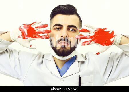 Chirurg mit dunklem Bart und ernsthaftem Gesichtsausdruck, der seine Hände im Blut zeigt, isoliert auf weißem Hintergrund. Konzept der Medizin und Rettungsdienst Stockfoto