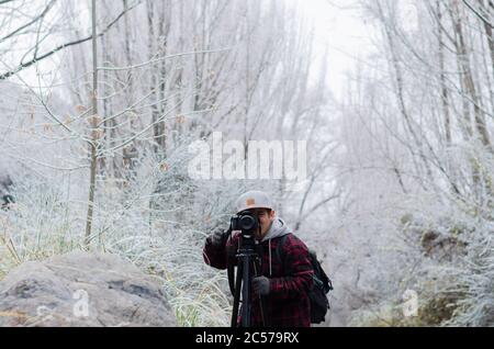 Selektiver Fokus ein junger männlicher Fotograf, der mit einem professionellen Fotografen fotografiert Fotokamera Stockfoto