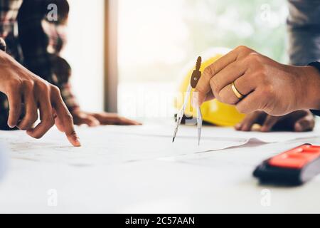 Zwei Architekten arbeiten auf der Baustelle und zeigen auf Blaupause. Stockfoto