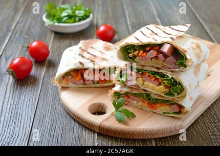 Lavaschwalzen mit Gemüse, Schinken und Käse. Leckere Vorspeise Frühstück auf einem Holzbrett. Stockfoto