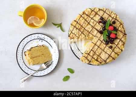 Klassische Napoleon-Torte. Köstliches festliches Dessert mit Blätterteig und Pudding, dekoriert mit frischen Beeren und einer Tasse Zitronentee. Die Ansicht von oben Stockfoto