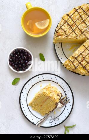 Klassische Napoleon-Torte. Köstliches festliches Dessert mit Blätterteig und Pudding, dekoriert mit frischen Beeren und einer Tasse Zitronentee. Die Ansicht von oben Stockfoto