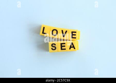 Love Sea Konzept, Schriftzug in gelben Buchstaben auf blauem Hintergrund Stockfoto