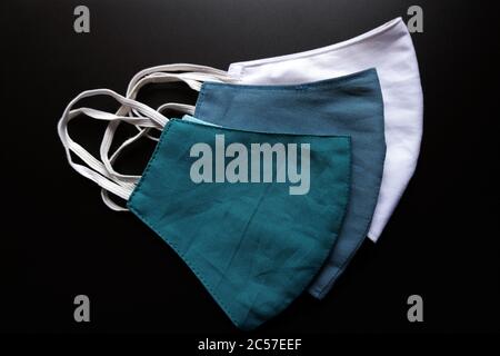 Overhead Aufnahme von drei verschiedenen farbigen Gesichtsmasken auf einem Schwarze Oberfläche Stockfoto