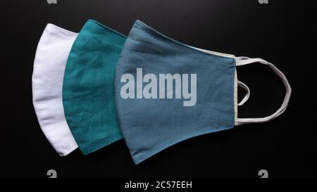Overhead Aufnahme von drei verschiedenen farbigen Gesichtsmasken auf einem Schwarze Oberfläche Stockfoto