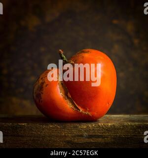 Beschädigte rote Tomate auf braunem Hintergrund isoliert Stockfoto