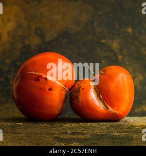 Beschädigte rote Tomate auf braunem Hintergrund isoliert Stockfoto