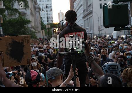 New York, Usa. Juli 2020. Ein Organisationschef der Gruppe Warriors wendet sich bei einem Protest vor dem Rathaus mit einem Megaphon an die Massen.die Spannungen nehmen vor einer Abstimmung des Stadtrates über New Yorks Budget zu, Das ist inklusive des Budgets der Polizeibehörde, da sich Demonstranten, die mit Black Lives Matter (BLM) und anderen Gruppen verbunden sind, in einem Protest vor dem Rathaus in Lower Manhattan versammeln, während sie weiterhin fordern, dass das New York City Police Department (NYPD) definanziert wird. Kredit: SOPA Images Limited/Alamy Live Nachrichten Stockfoto