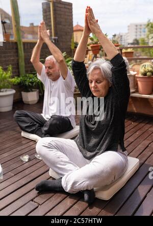 Vertikales Foto eines älteren Paares, das Gott auf der von Pflanzen umgebenen Holzterrasse begrüßt Stockfoto