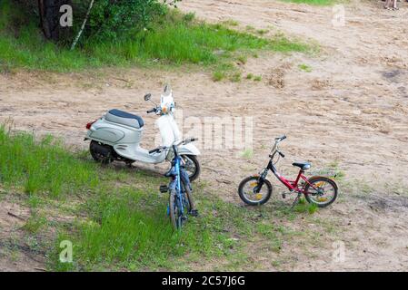 Ein altes Moped und zwei Fahrräder stehen auf dem Sand. Vintage-Ausrüstung. Stockfoto