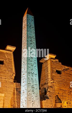 Großer Obelisk am Eingangspylon zum altägyptischen Luxor Tempel, der nachts beleuchtet wird Stockfoto