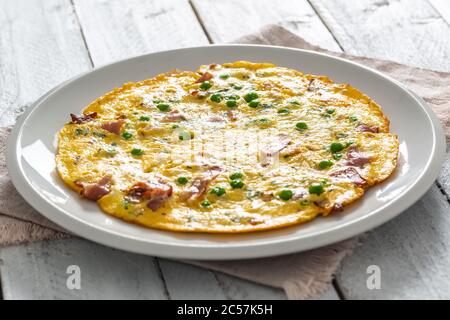 Omelette mit Prosciutto Erbsen und Kräutern auf weißem Teller Stockfoto