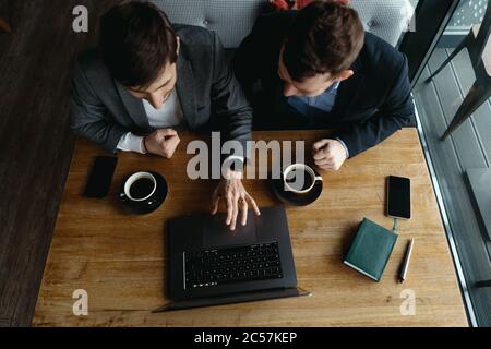 Zwei Geschäftsleute sprechen über neue Möglichkeiten, mit einem Laptop am Schreibtisch zu sitzen, ein Projekt zu planen, Geschäftsangebote in Betracht zu ziehen und Ideen zu teilen Stockfoto