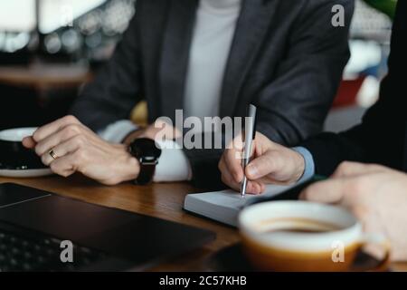 Zwei Geschäftsleute sprechen über neue Möglichkeiten, mit einem Laptop am Schreibtisch zu sitzen, planen ein Projekt, wenn sie ein Geschäftsangebot in Betracht ziehen Stockfoto