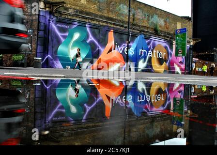 EINE PFÜTZE REFLEKTIERTE SCHWARZE LEBEN MATERIE WANDBILD AUF DER GROSSEN EASTERN STREET, LONDON Stockfoto