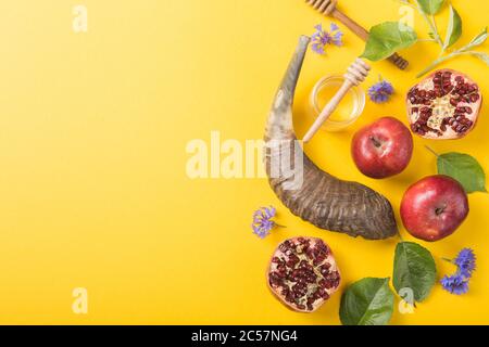 Rosh hashanah - jüdisches Neujahrsfest-Konzept. Traditionelle Symbole: Honigglas und frische Äpfel mit Granatapfel und Schofar -Horn auf einem gelben Backgr Stockfoto