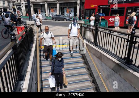 Oxford Circus unter dem Bahnhofseingang während einige nicht unbedingt notwendige Geschäfte wieder geöffnet werden, kehren die Käufer in die Oxford Street zurück, während die verschiedenen Einzelhandelsgeschäfte, die am 26. Juni 2020 in London, England, Großbritannien, geöffnet sind, soziale Distanzierungsmaßnahmen ergreifen. Da die Frist für den Juli näher kommt und die Regierung ihre Sperrregeln weiter lockern wird, bleibt das West End ruhig, abgesehen von diesem beliebten Einkaufsviertel, das selbst weit weniger Menschen auf seinen Gehwegen hat als normal. Stockfoto