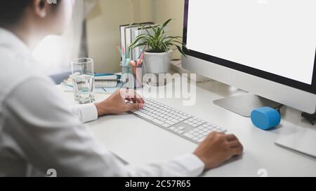 Der Büroangestellte arbeitet mit einem weißen Bildschirm Computer am weißen Schreibtisch. Stockfoto