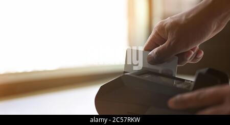 Zugeschnittenes Bild der Hände zieht eine Kreditkarte auf den Kartenleser. Stockfoto