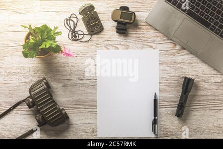 Heller Schreibtisch aus Holz mit Laptop, gps und leerem Papiertuch, Kompass, Fernglas und leerem Blatt Papier Stockfoto